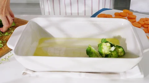Fresh broccoli being added to an oiled baking dish for roasting. Stock Footage 308170455