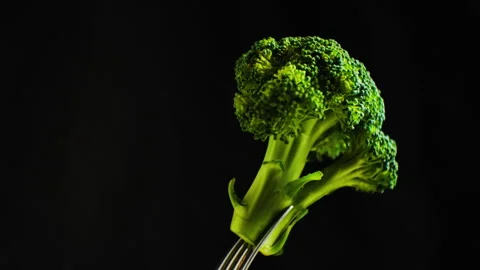 Fresh broccoli florets rise on a fork against a dark backdrop, conveying health, Stock Footage 291732326