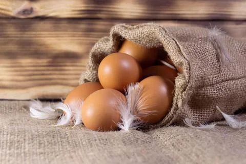 Fresh brown chicken eggs in a sacking on wooden background. Easter holidays c Stock-Fotos