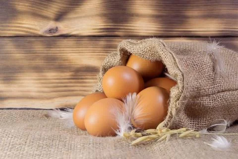Fresh brown chicken eggs in a sacking on wooden background. Easter holidays c Foto stock