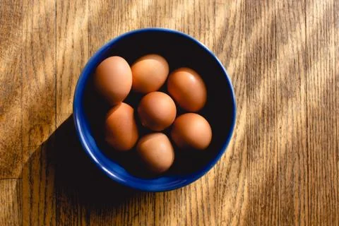 Fresh brown eggs in ceramic blue bowl Stock Photos