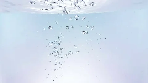 Fresh bubbles splash falling down into water, shot in slow motion on white Stock Footage 77359946
