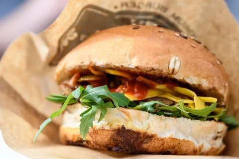 Fresh burger with pulled meat, cheese and fresh arugula leaves at a food market Stock Photos