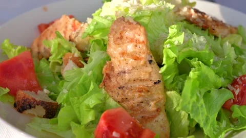 Fresh caesar salad with grilled chicken breast pieces and tomato slices in .. Stock Footage 339644777