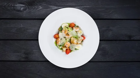 Fresh caesar salad rotating on white plate with parmesan cheese and shrimps. Is Stock Footage 129185584