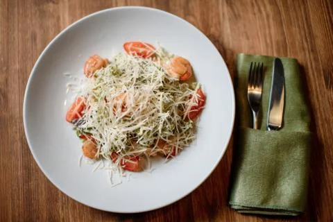 Fresh caesar shripm salad on white dish wooden table. top view Stock-Fotos
