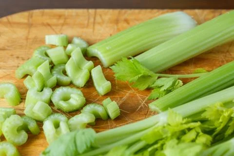 Fresh celery cut into small pieces on wooden board Foto stock
