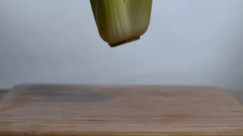 Fresh celery falling in slow motion on chopping board Stock Footage 100007920