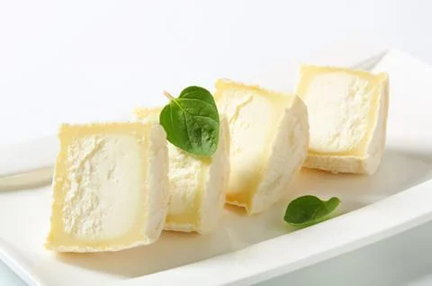 Fresh cheese cubes with mint garnish on plate Stock Photos