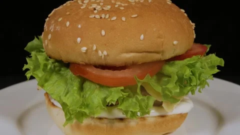 Fresh cheeseburger rotating on a white plate, isolated on a black background Stock Footage 314330358