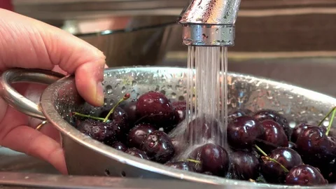 Fresh cherries being washed in a strainer above a sink 動画素材 91723540