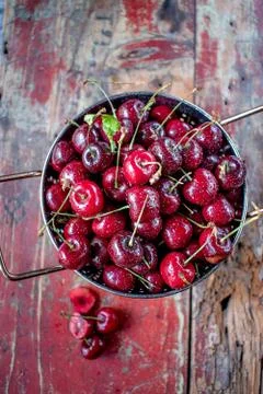 Fresh cherries in copper strainer on rustic farmhouse table Stock Photos