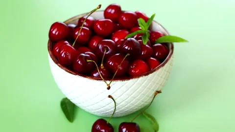 Fresh cherries with mint leaves on pastel green background Stock Footage 340415754