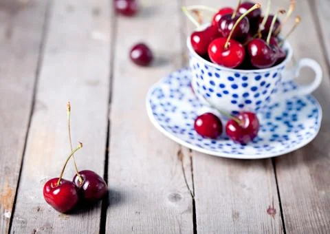 Fresh cherry in a blue ceramic cup on a wooden background Stock Photos