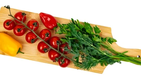 Fresh cherry tomatoes, bell pepper, and green herbs on wooden cutting Stock Footage 348237709