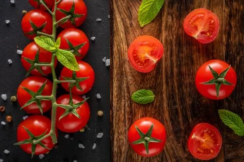 Fresh cherry tomatoes on a black background with spices. Stock Photos