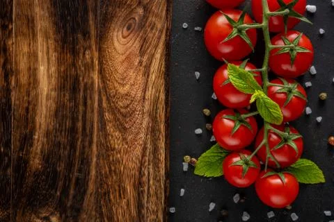 Fresh cherry tomatoes on a black background with spices. Food background. 写真素材