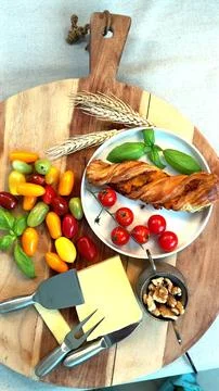 Fresh cherry tomatoes, cheese slice, basil leaves, flaky twist pastry on wooden Stock Photos