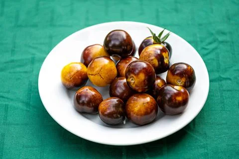 Fresh cherry tomatoes of different varieties on a plate on the blurred backgr Stock Photos