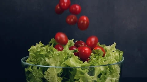 Fresh cherry tomatoes falling on lettuce on black background 스톡 동영상 306677887