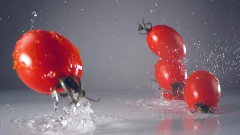 Fresh cherry tomatoes falling on water surface. Slow Motion. Stock Footage 128772427