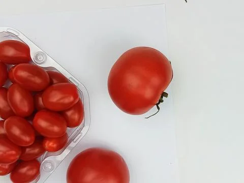 Fresh cherry tomatoes in plastic container with ripe tomatoes on white backgroun Stock Photos
