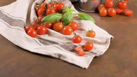 Fresh cherry tomatoes on a striped kitchen towel with basil leaves Stockfoto's