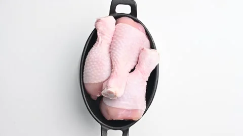 Fresh chicken drumsticks ready for cooking in a cast iron dish at a clean Stock Footage 305227269