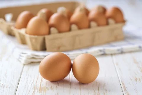 Fresh chicken eggs on a light kitchen table, selective focus Stock Photos