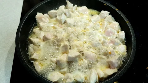Fresh chicken meat cut into cubes fried in a frying pan Stock Footage 127776323