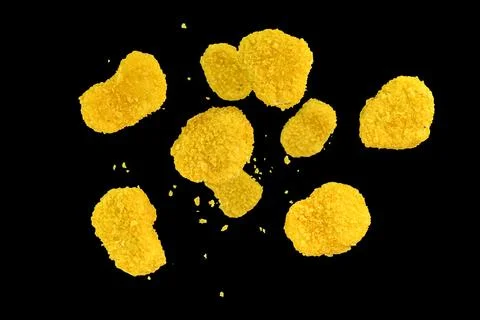 Fresh chicken nuggets falling on black background. Freeze motion of flying .. Fotos de archivo