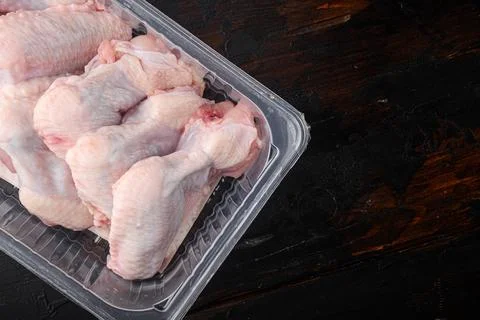 Fresh chicken wings spit in plastic vacuum pack, on old dark wooden table bac Foto stock