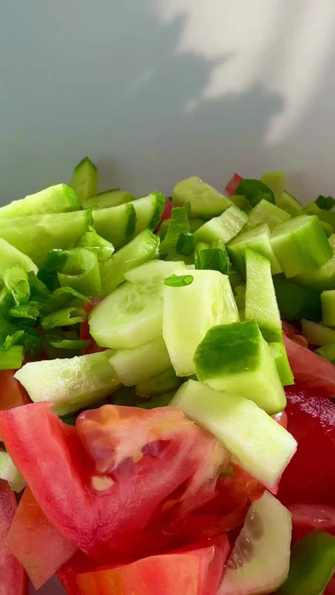Fresh chopped cucumbers and tomatoes in bowl with onions Video stock 331976531