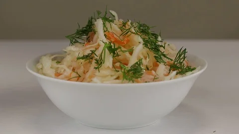 Fresh chopped dill is added to a white bowl Stock Footage 121886928