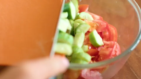 Fresh chopped tomatoes and cucumbers in a glass bowl on a wooden table Stock Footage 271223536