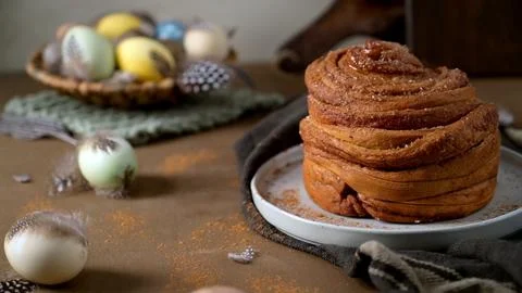 Fresh Cinnamon Roll with Easter Eggs and Spring Decor Stock Photos