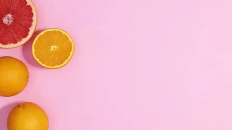 Fresh citrus fruits appear on left side of pastel pink background. Stop motion Stock Footage 152897953