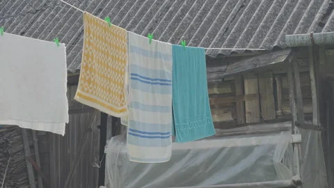 Fresh clean laundry hanging on a clothesline and drying in the wind. Rustic Stock Footage 343963597
