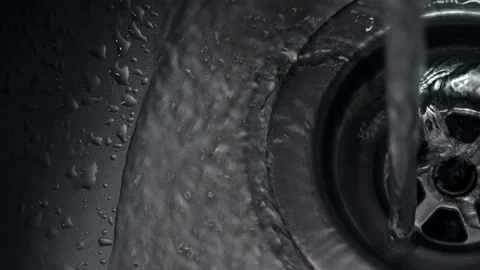 Fresh clean water running down plug hole in stainless steel sink Vídeos de archivo 104784473