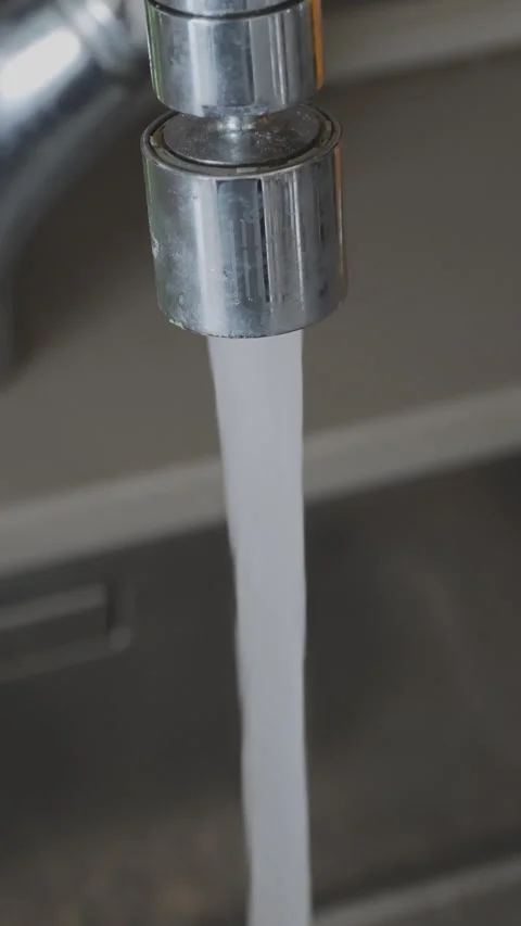 Fresh clean water running from a modern tap in a kitchen. Close up on the metal Stock Footage 346184302