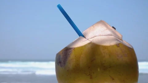 Fresh coconut drink with blue straw on the beach with sea background Stock Footage 256271564