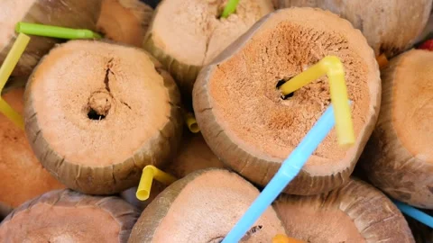 Fresh coconut drinks served with colorful straws at a local market Stock Footage 345697126