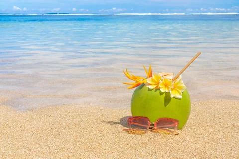 Fresh coconut juice with sunglasses on the background of a beautiful beach. Stock Photos