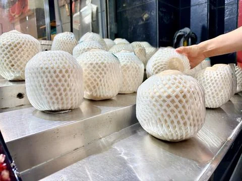Fresh Coconuts Wrapped in Protective Foam on Market Display Stock Photos