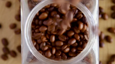 Fresh coffee beans falling into a jar Stock Footage 130423825