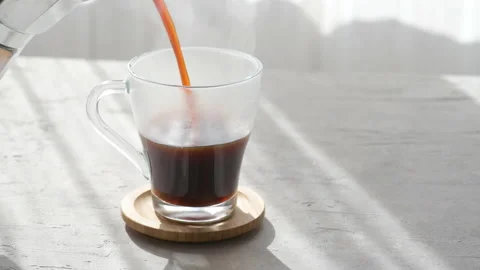 Fresh coffee is pouring from a mocha in a transparent coffee cup, morning coffee Stock Footage 176861476