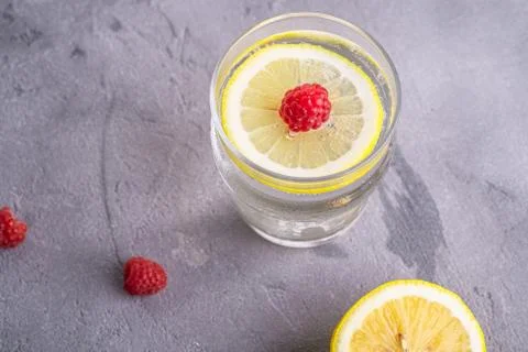 Fresh cold sparkling water drink with lemon, raspberry fruits in glass Stock Photos
