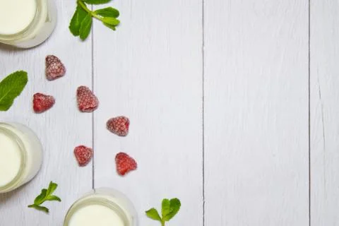 Fresh composition with yogurt in cans of mint leaves and frozen raspberries Stock Photos