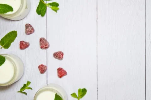 Fresh composition with yogurt in cans of mint leaves and frozen raspberries Stock Photos