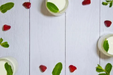 Fresh composition with yogurt in cans of mint leaves and frozen raspberries Stock Photos